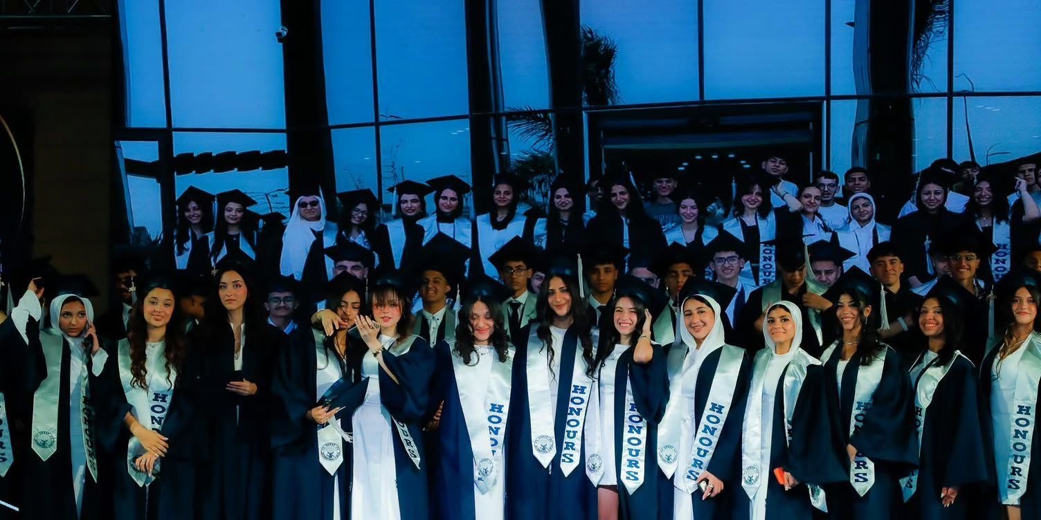 The Globe graduates in caps and gowns in front of the school